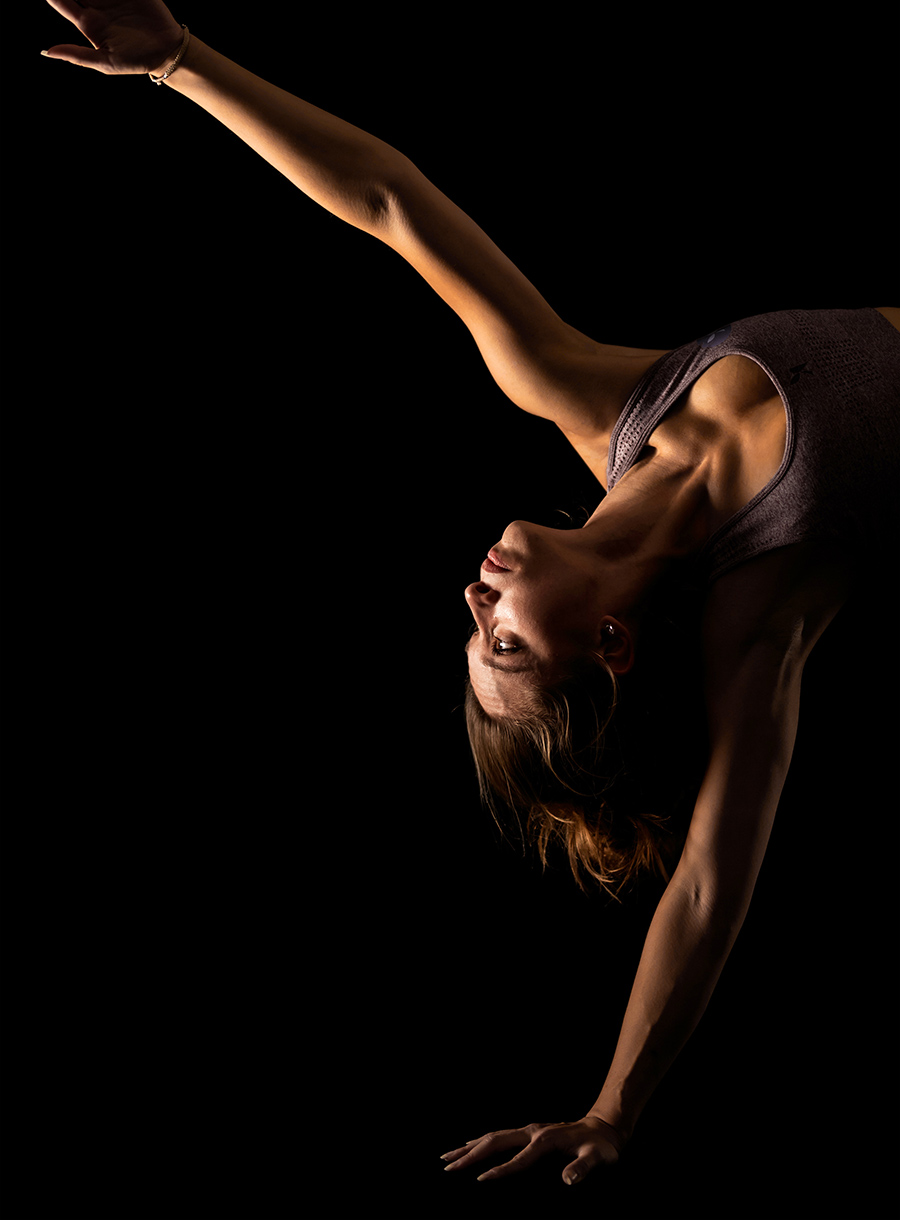 Closeup of woman doing single arm stretch by reaching toward the ceiling upside down